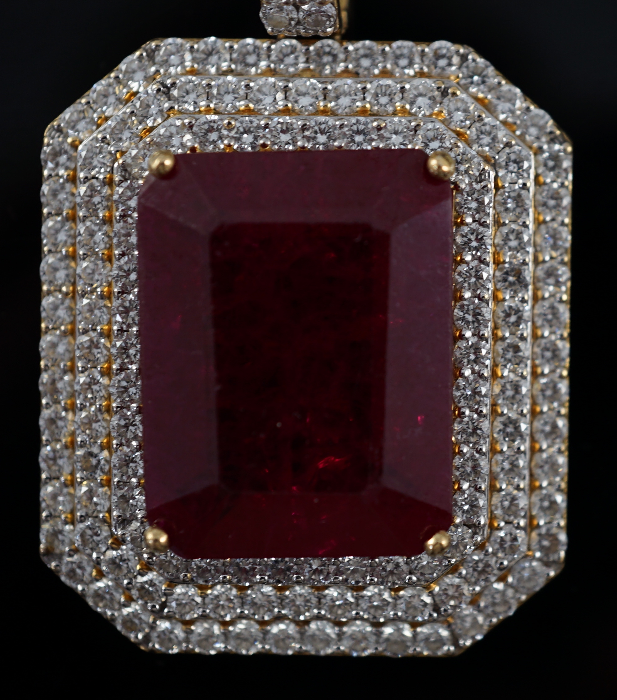 A large modern 18ct gold and single emerald cut synthetic ruby set pendant, bordered by three concentric bands of round brilliant cut diamonds